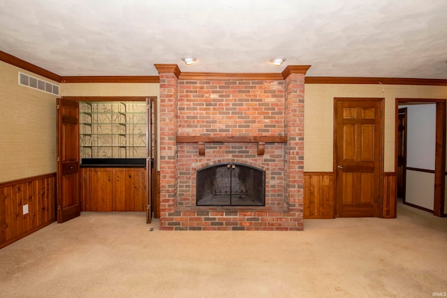 unfurnished living room featuring light colored carpet, ornamental molding, a fireplace, and wooden walls