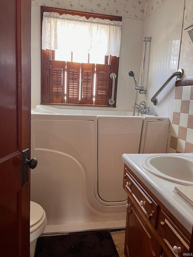 bathroom featuring a bath, vanity, and toilet