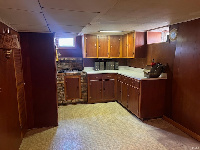 kitchen with a paneled ceiling, wood walls, and light colored carpet