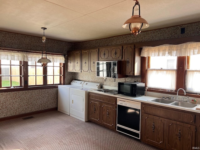 kitchen with sink, hanging light fixtures, dark colored carpet, independent washer and dryer, and black appliances