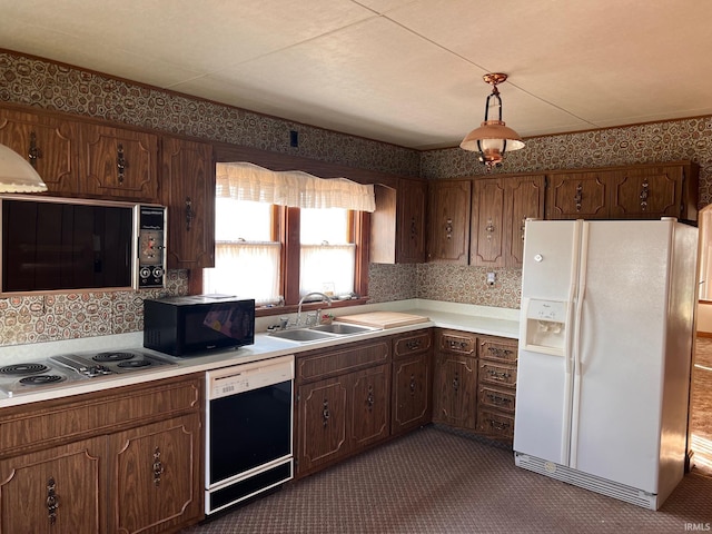 kitchen featuring sink, black appliances, decorative light fixtures, and dark carpet