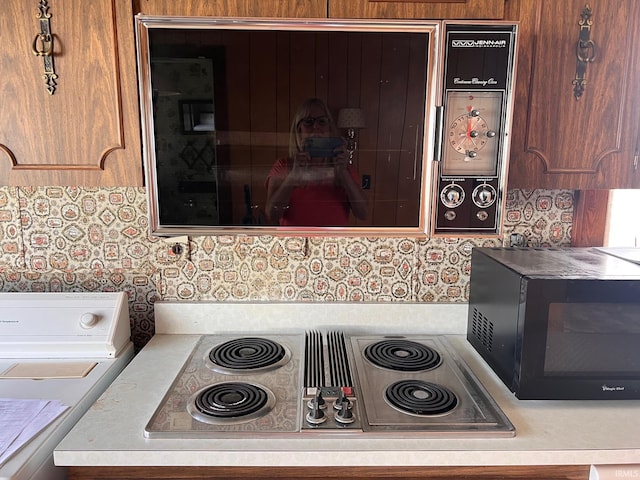 room details featuring stainless steel electric stovetop and washer / dryer