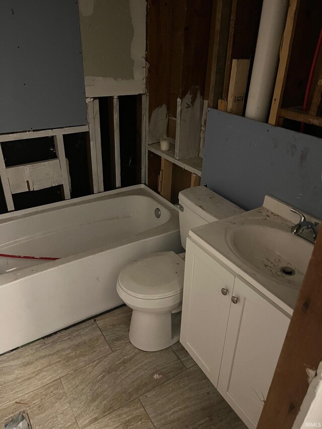 bathroom featuring a tub, vanity, and toilet