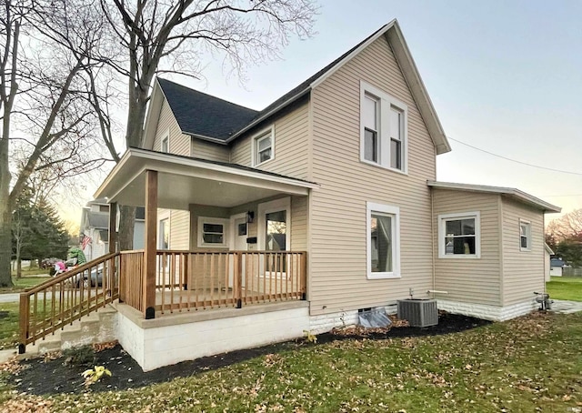 rear view of house with central AC, a yard, and a porch