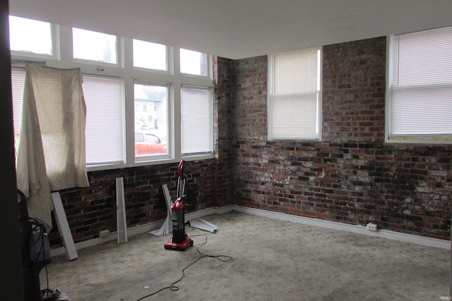 unfurnished room featuring carpet and brick wall