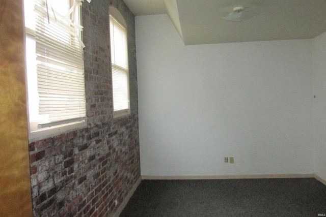 carpeted spare room with brick wall