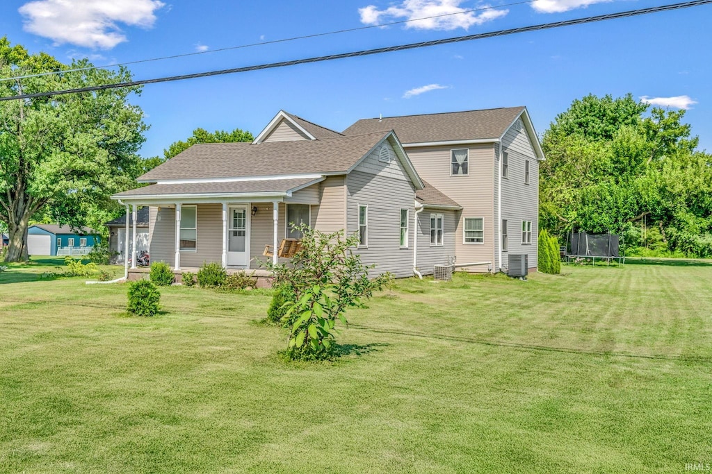 view of front facade featuring a front lawn, cooling unit, a porch, and a trampoline