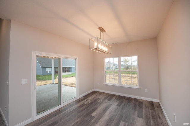 unfurnished dining area with an inviting chandelier and dark wood-type flooring