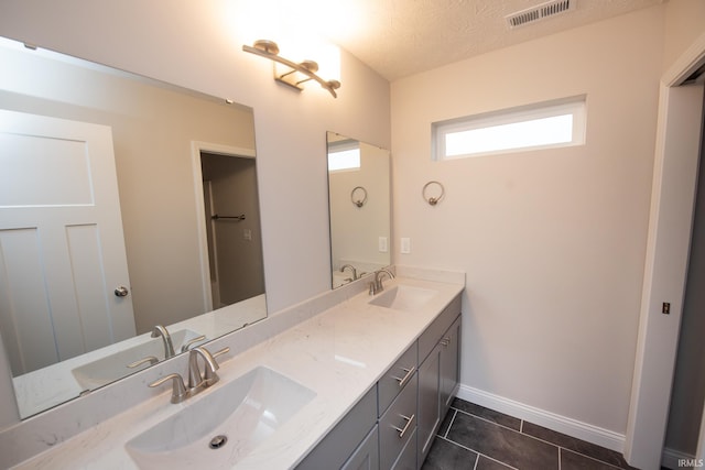 bathroom with tile patterned flooring, a textured ceiling, and vanity