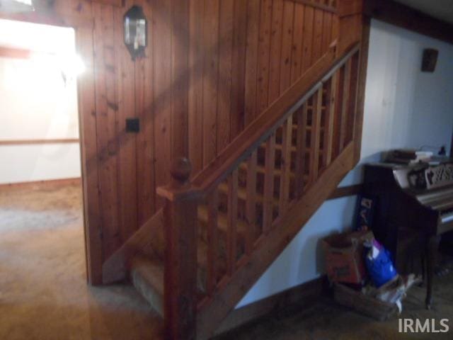 stairway featuring wood walls