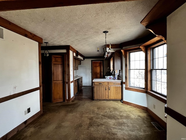 kitchen featuring sink, hanging light fixtures, a textured ceiling, and dark carpet