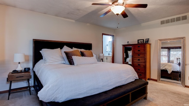 bedroom with carpet, a textured ceiling, ensuite bathroom, and ceiling fan