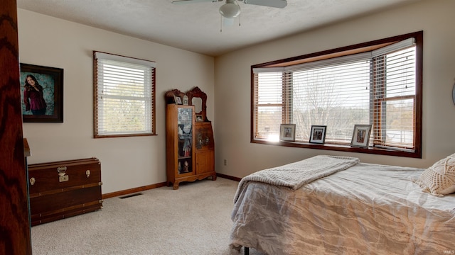 bedroom with multiple windows, ceiling fan, light carpet, and a textured ceiling