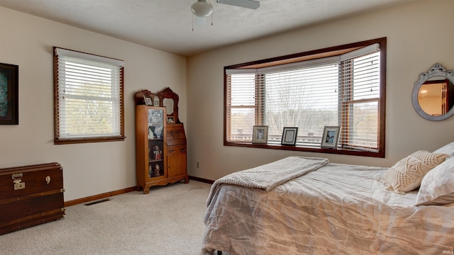 bedroom featuring ceiling fan, light carpet, and a textured ceiling