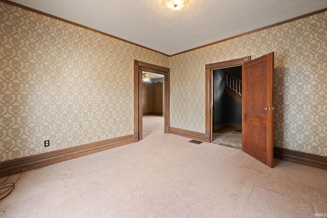 unfurnished room with ceiling fan, light colored carpet, a textured ceiling, and ornamental molding