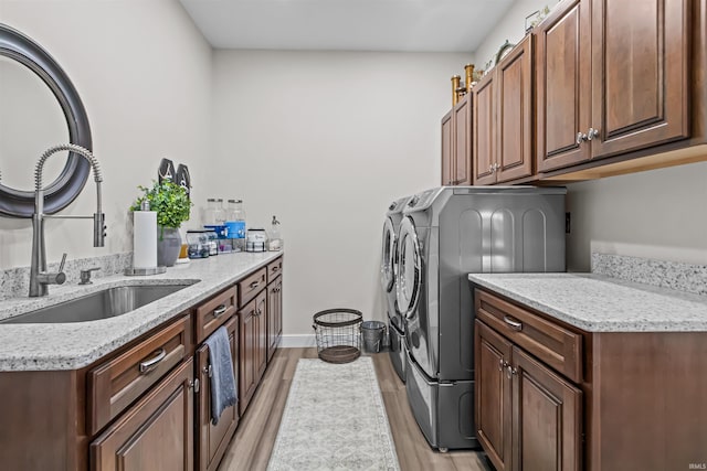 laundry room with independent washer and dryer, cabinets, light wood-type flooring, and sink