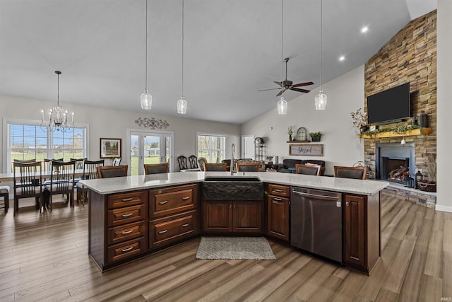 kitchen featuring sink, stainless steel dishwasher, a fireplace, decorative light fixtures, and a kitchen island