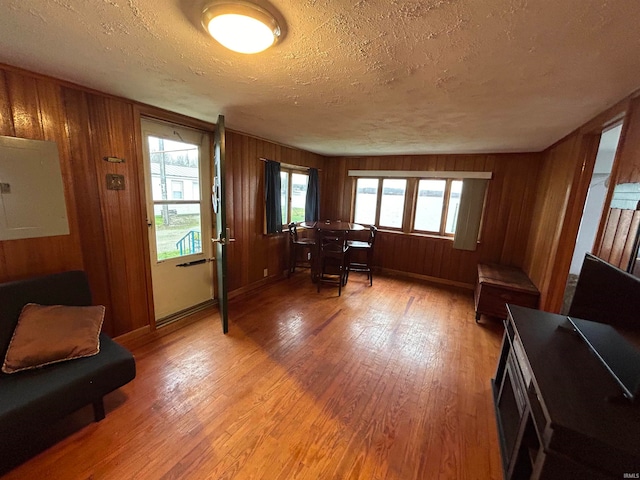 interior space with a textured ceiling, hardwood / wood-style flooring, and wood walls