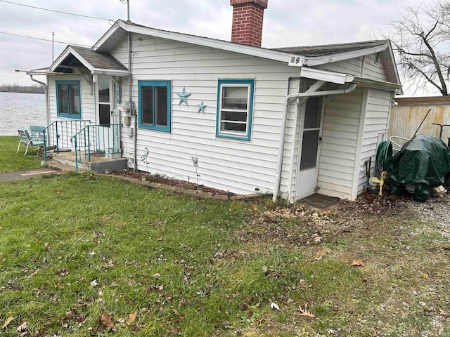 back of house featuring a water view and a lawn