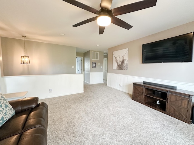 carpeted living area featuring ceiling fan, visible vents, and wainscoting