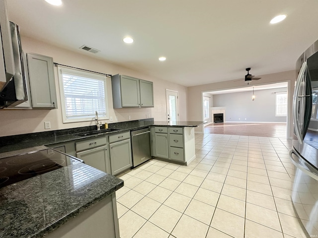 kitchen featuring a fireplace, visible vents, appliances with stainless steel finishes, a sink, and a peninsula