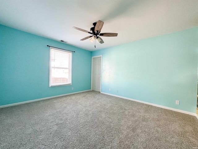 empty room with a ceiling fan, carpet flooring, visible vents, and baseboards