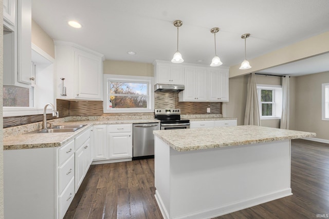 kitchen featuring white cabinets, sink, appliances with stainless steel finishes, decorative light fixtures, and extractor fan