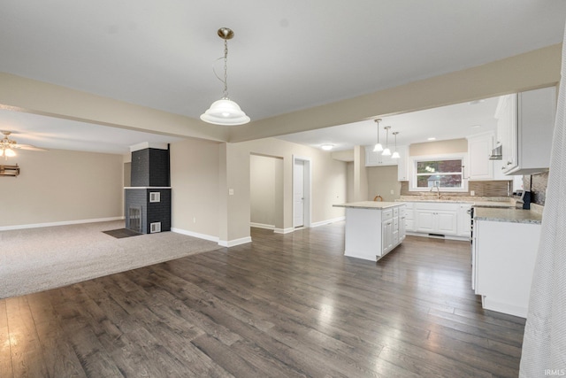 kitchen with a center island, sink, hanging light fixtures, dark hardwood / wood-style flooring, and white cabinetry