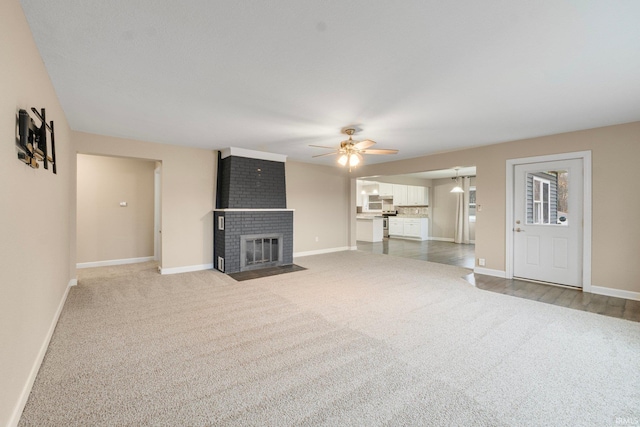 unfurnished living room featuring ceiling fan, a fireplace, and carpet floors