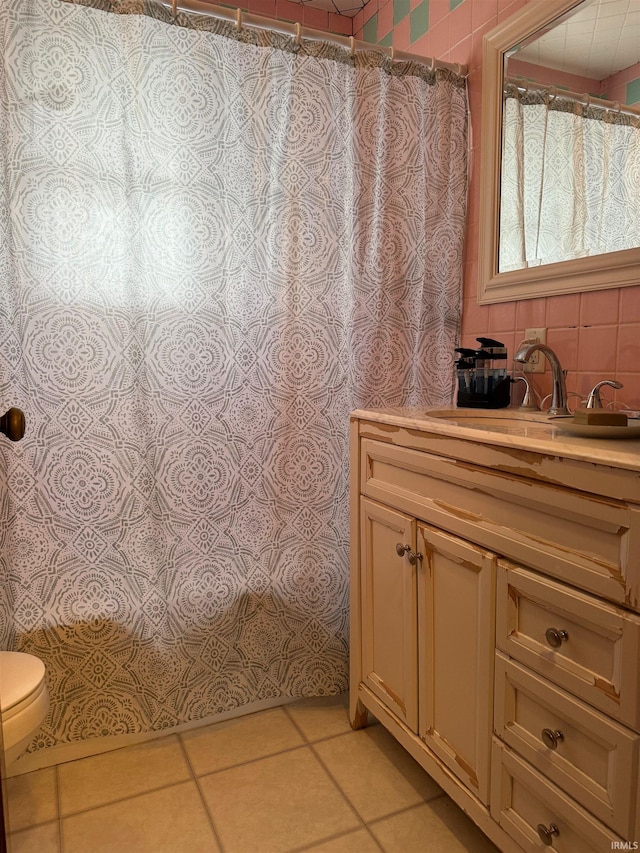 bathroom with tile patterned floors, walk in shower, vanity, tile walls, and toilet