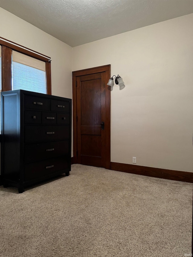 unfurnished bedroom featuring a textured ceiling and light colored carpet