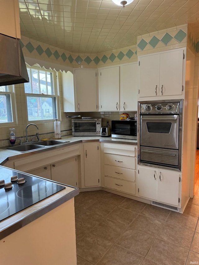 kitchen featuring light tile patterned floors, sink, white cabinetry, and black appliances