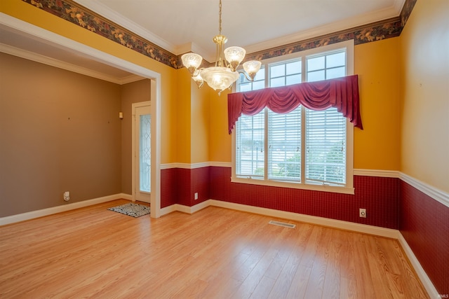 spare room with hardwood / wood-style flooring, crown molding, and an inviting chandelier