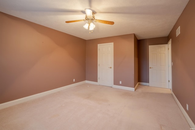 unfurnished bedroom with ceiling fan, light colored carpet, and a textured ceiling