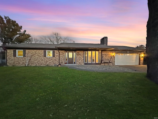 back house at dusk featuring a yard and a garage