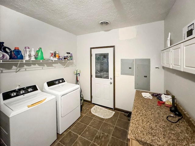 laundry room with a textured ceiling, washing machine and dryer, electric panel, and dark tile patterned flooring