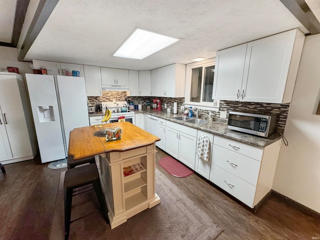 kitchen with white appliances, sink, dark hardwood / wood-style floors, tasteful backsplash, and white cabinetry