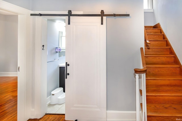 stairs with hardwood / wood-style flooring and a barn door