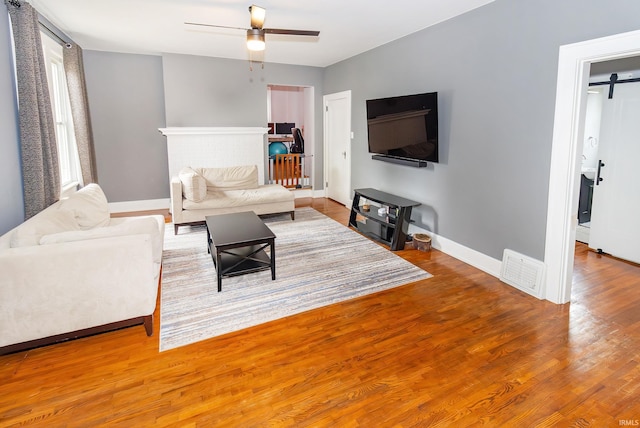 living room featuring hardwood / wood-style floors, a barn door, and ceiling fan