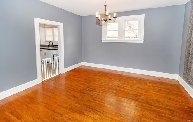 unfurnished room with plenty of natural light, wood-type flooring, and a notable chandelier