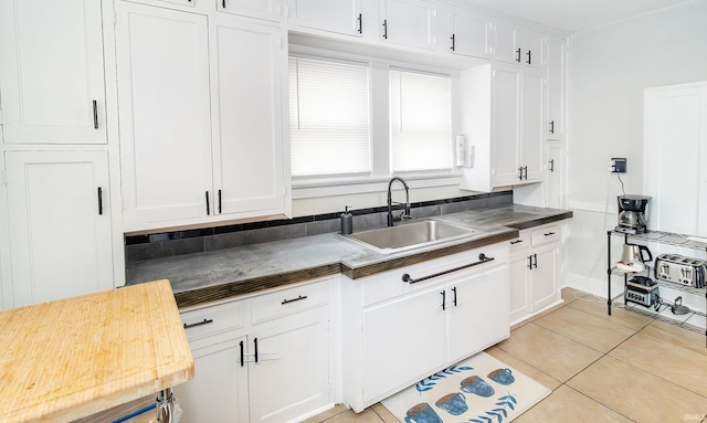 kitchen featuring light tile patterned floors, white cabinetry, and sink