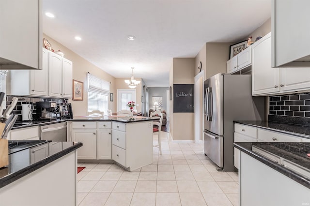 kitchen with white cabinets, hanging light fixtures, tasteful backsplash, kitchen peninsula, and stainless steel appliances