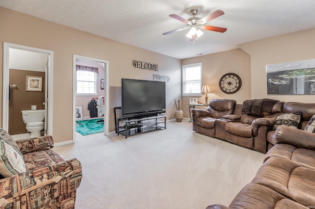 carpeted living room with a wealth of natural light, ceiling fan, and a textured ceiling