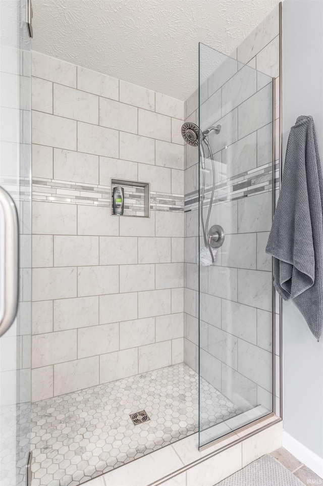 bathroom with tile patterned flooring, a textured ceiling, and walk in shower