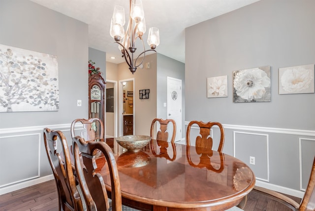 dining area featuring dark wood-type flooring and an inviting chandelier