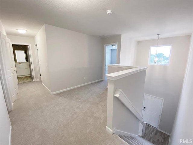 corridor featuring a chandelier and light colored carpet