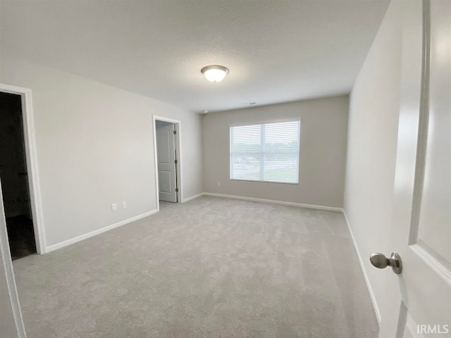 unfurnished bedroom with a spacious closet, light carpet, and a closet