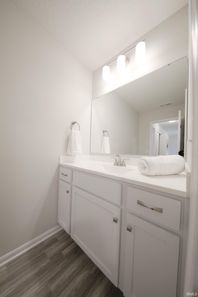 bathroom with hardwood / wood-style floors, vanity, and a textured ceiling