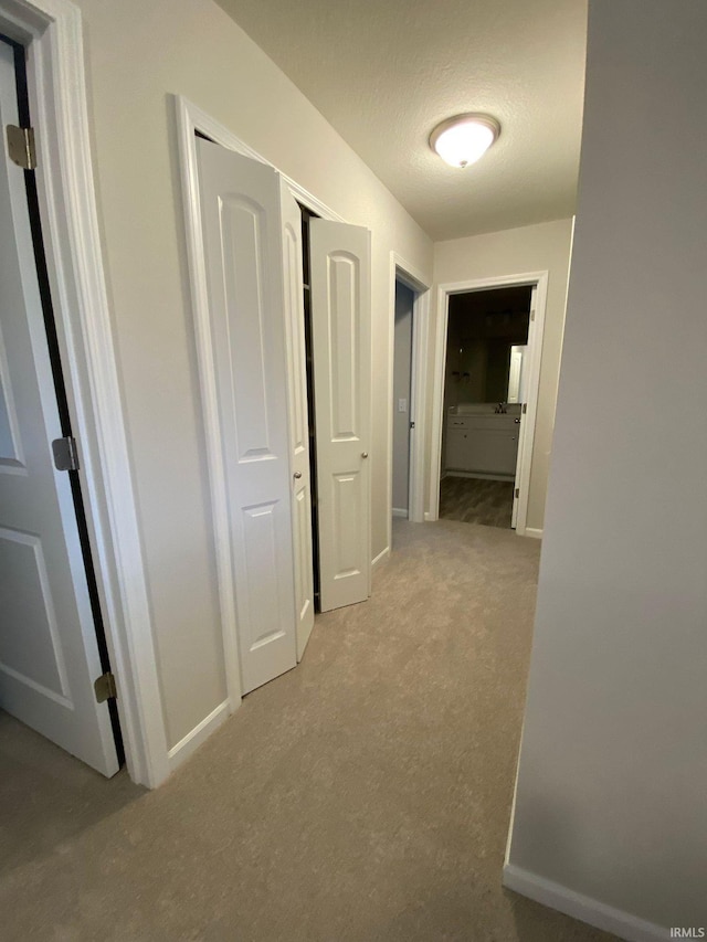 corridor with a textured ceiling and light carpet