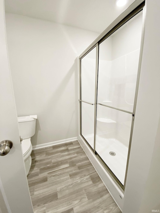 bathroom with hardwood / wood-style flooring, toilet, and an enclosed shower